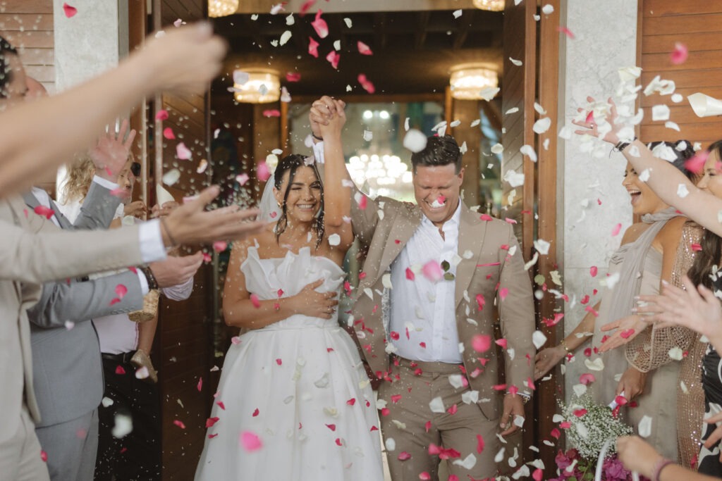 Bride and groom in pink petal confetti toss