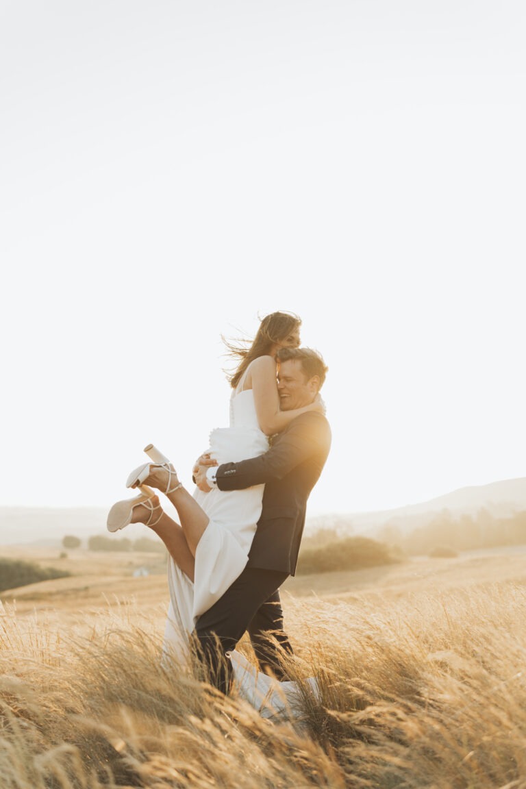 Groom picking up bride with sunset