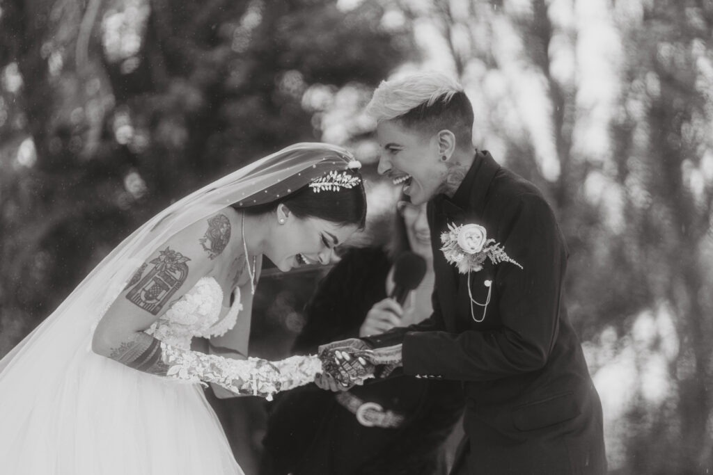 LGBTQ+ couple laughing during their ceremony