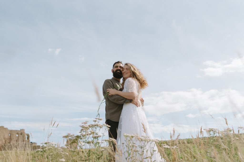 Couple cuddling underneath blue sky in Scotland