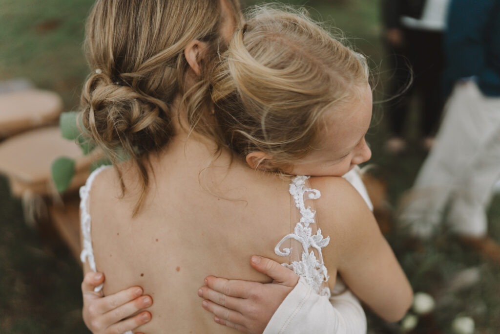 Candid moment of bride and flower girl hugging