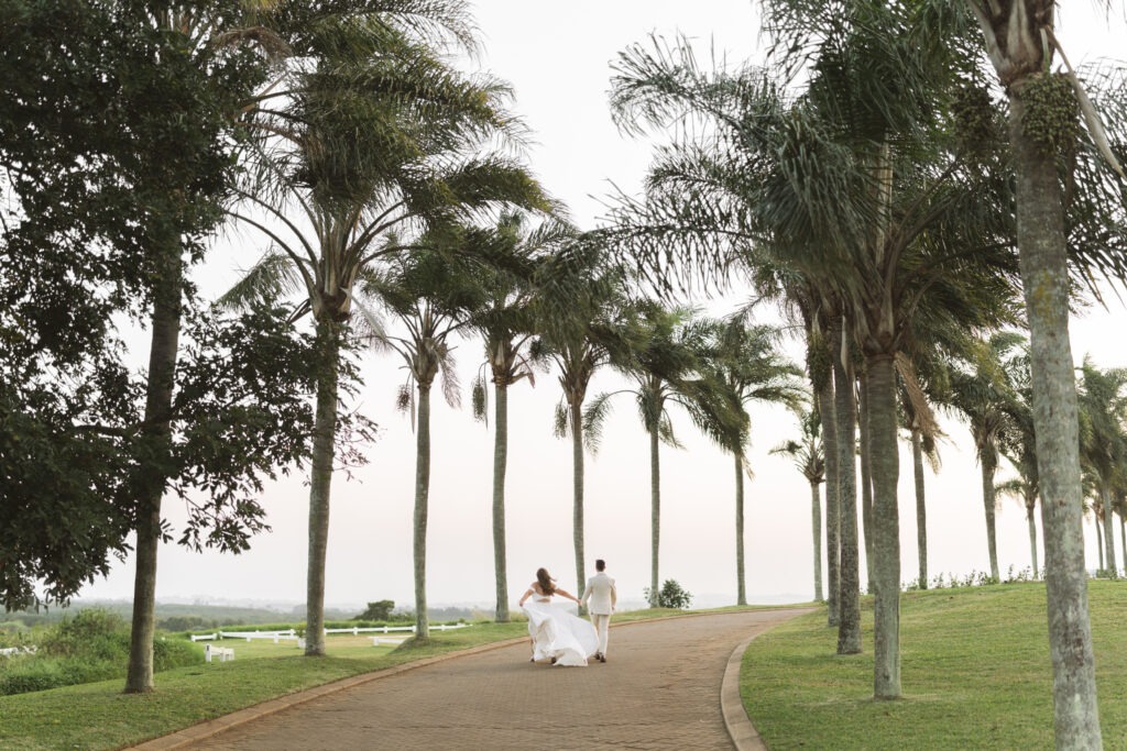 Bride and groom running under palm trees in Durban, South Africa