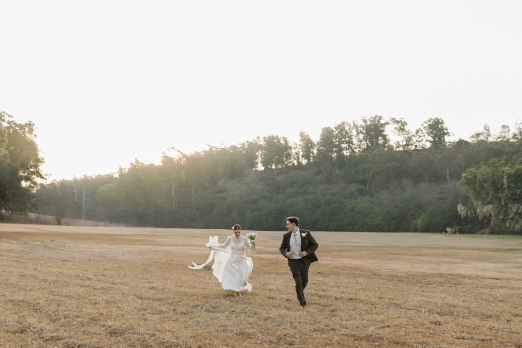 bride and groom running in field