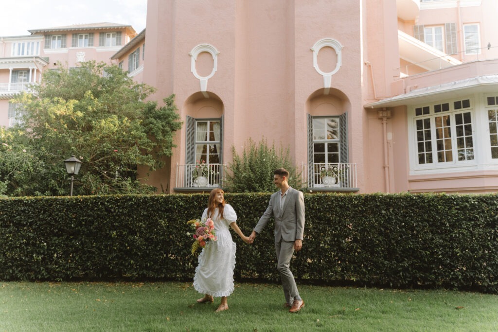 Bride and groom walking together at beautiful, pink location in Cape Town