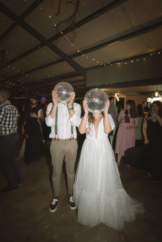 Artsy couple holding disco balls at their wedding