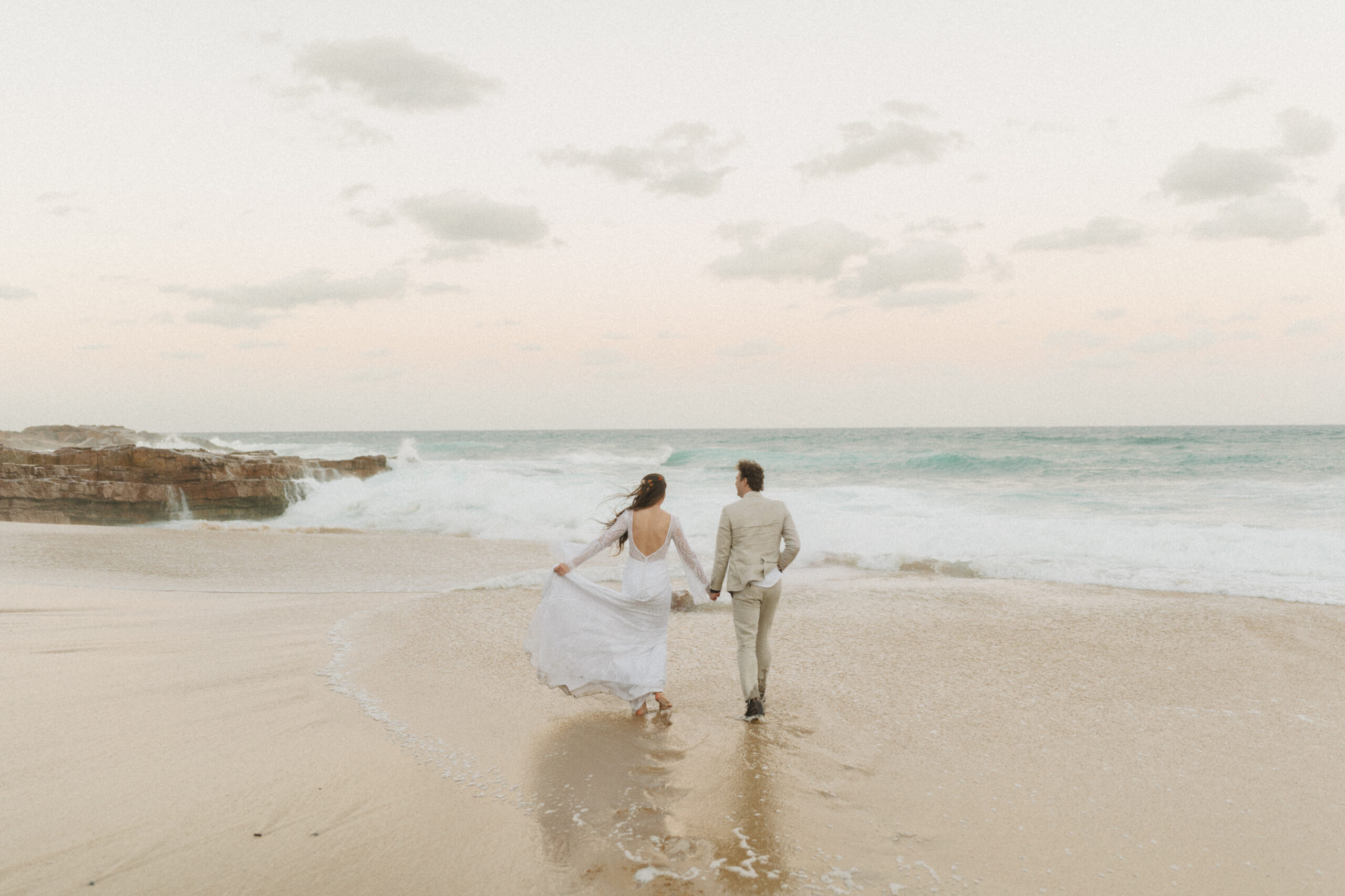 Bridal couple running into sunset on Cape Town beach