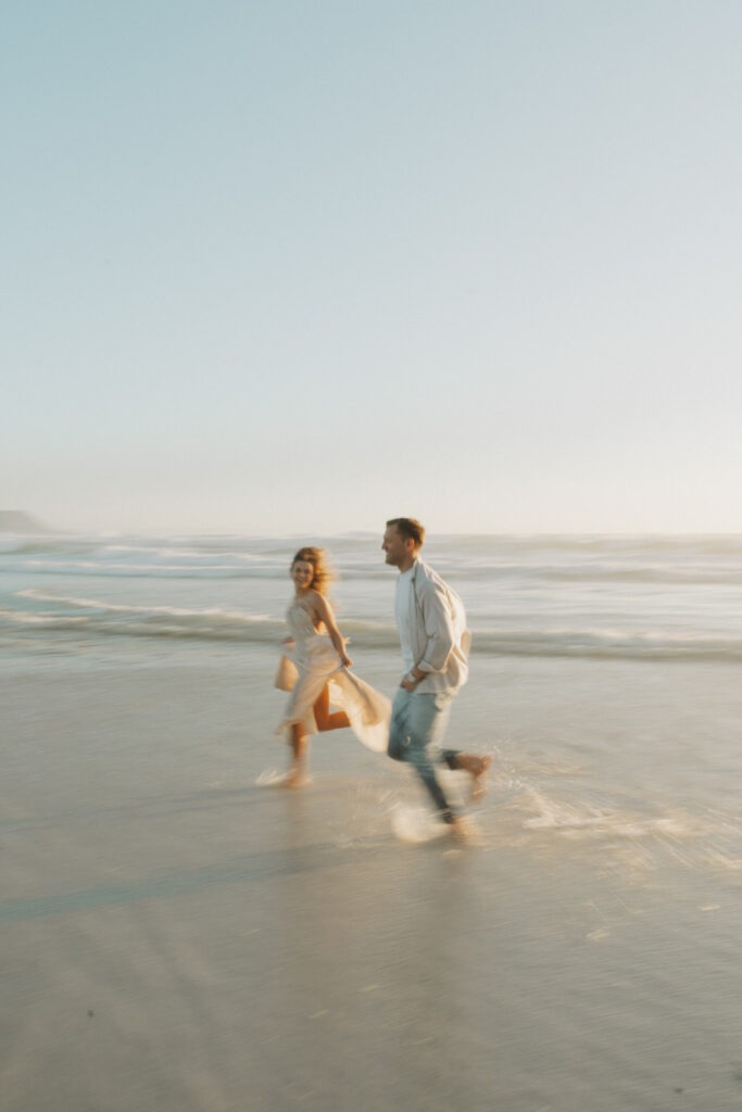 Fun, filmy and fine-art wedding photography of couple running on beach in Noordehoek, Cape Town